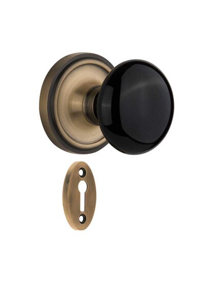 Classic Rosette Mortise-Lock Set with Black Porcelain Knobs in Antique Brass.